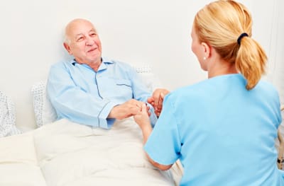 Nurse holds the hands of a senior as a patient in the hospital